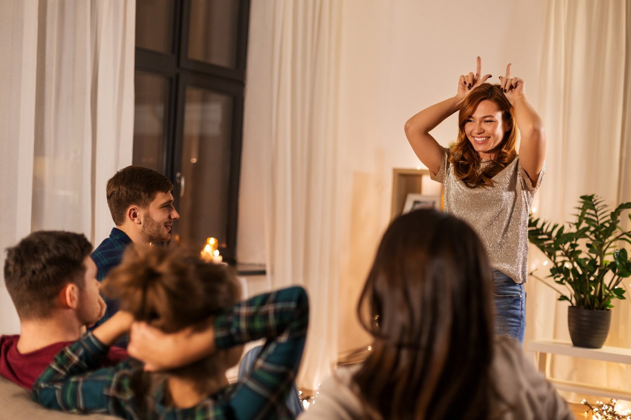 Happy Friends Playing Charades at Home in Evening